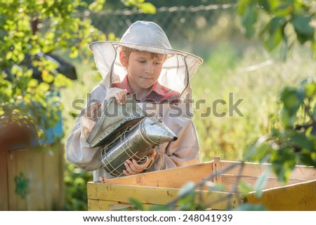 Teenage beekeeper smoking hive in a bee yard