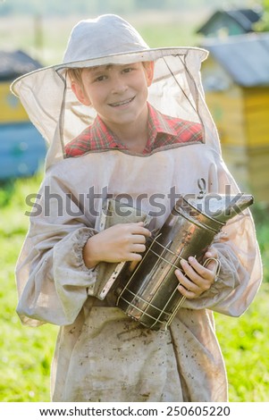 Young beekeeper boy checking hives on bee yard