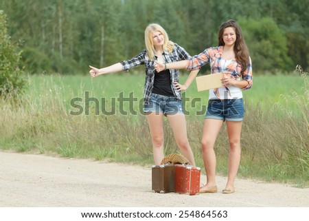 Students girls hitchhiking with an empty cardboard