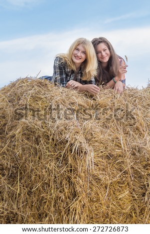 Portrait of student friends are lying on big round straw bale