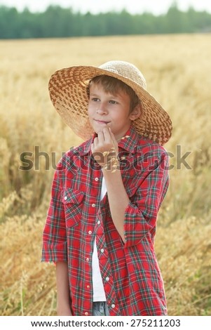 Teenage young family farm worker in wide-brimmed hat and oat cereal ears straw in mouth