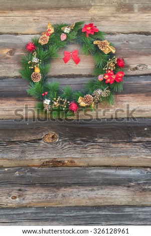 Festive outside X-mas spruce wreath at old grey log cabin wall background