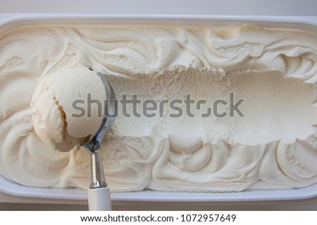 Vanilla ice cream Flat lay. Top view. Spoon for ice cream takes a little out of the package. Macking ball of ice cream. Space for text.