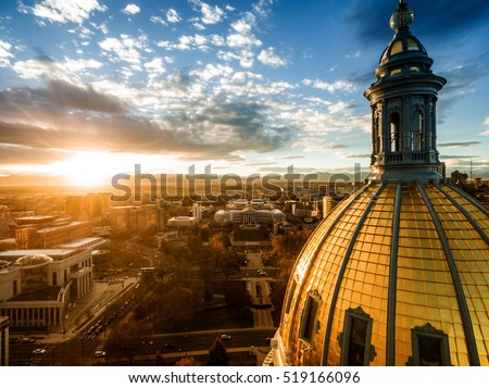Aerial/Drone photograph of a sunset over the Colorado state capital building in Denver.  The Rocky Mountains can be seen on the horizon