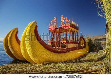 Reed boat on Island of Uros. Those are floating islands on lake Titicaca located between Peru and Bolivia. Colorful image with yellow boat and clear blue sky.