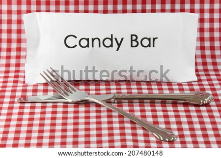 A white candy bar wrapper with a knife and fork on a red gingham background.
