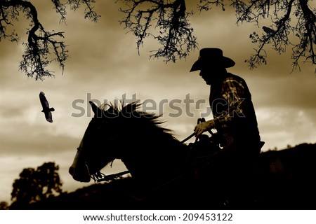 A cowboy gallops down a hill to escape danger.  Sepia tone, black branches, and birds.