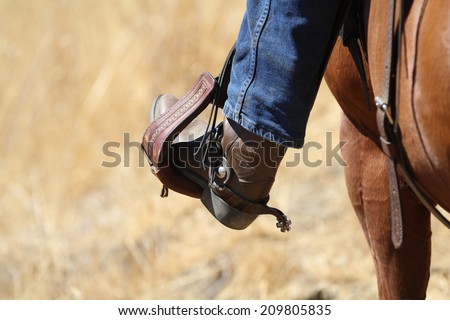 A cowboy boot in saddle stirrup.