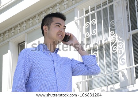 Head shot of a young Asian man using a cell phone taken from a low angle