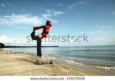 Woman practicing a yoga balance by the sea