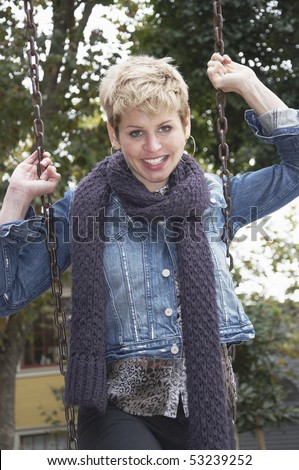 Trendy woman holds on to the chains of the swing she is standing on