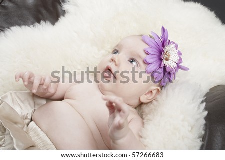 A young baby laying on a sheepskin rug