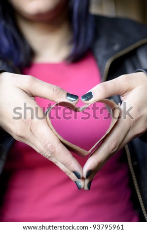 a woman holding a heart formed with the insulating sleeve from a coffee cup