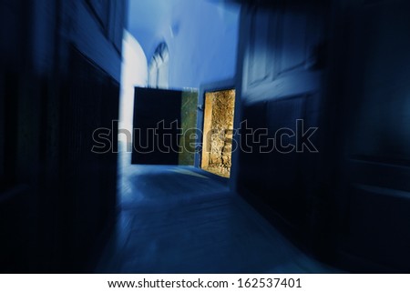 Open door with yellow light to dark blue passage