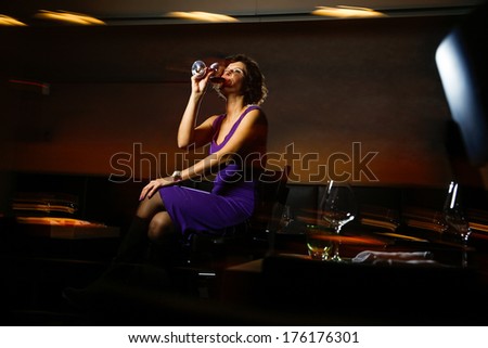 Beautiful lady in dress drinking wine in nightclub