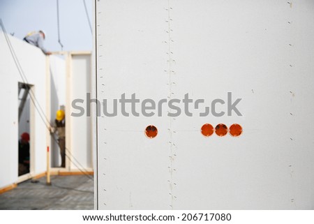 Electricity sockets in a drywall with tubing for wires and workers in the background