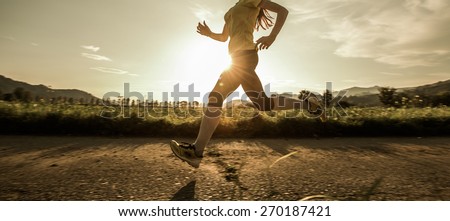 Fit woman running fast, training in bright sunshine