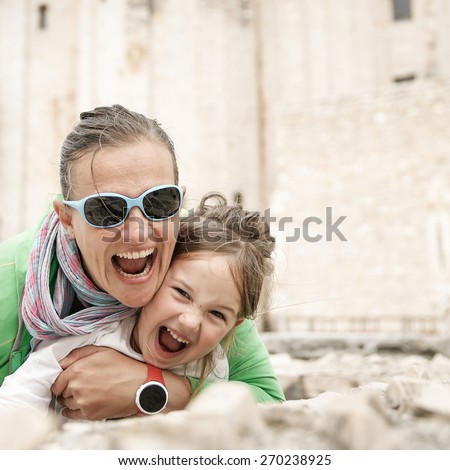 Playful Caucasian mother and daughter hugging, joking, making funny faces, smiling and having fun traveling and enjoying the summer. Natural, real situation.