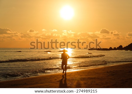 Silhouette of a fit runner at sunset on a sandy beach, enjoying the evening chill of late summer. Active lifestyle, vacation recreation, outdoor activity concept.