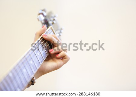 Woman musician holding a guitar, learning, playing a G chord. Self-teaching, artistry, skill concept, musical background.