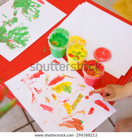Child painting a drawing with finger paints, used for finger drawing and sensory play. Fun childhood, sensory and experience-based learning concept.