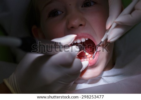 Little girl at paediatric dentists office, getting her teeth polished with prophylactic paste by her dentist. Early prevention, oral hygiene, fear of dentist and milk teeth care concept.