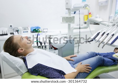 Patient sitting on dental chair wearing dental bib, waiting for her dentist. Dental medicine, dental care, prevention, health concept.