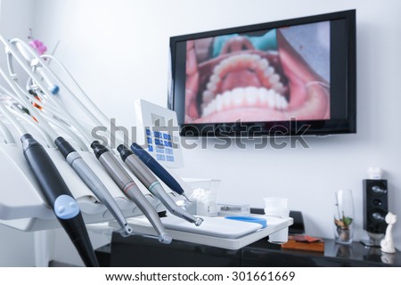 Dental office - specialist tools, drills, handpieces and laser with live picture of teeth in the background. Dental care, dental hygiene, checkup and therapy concept.
