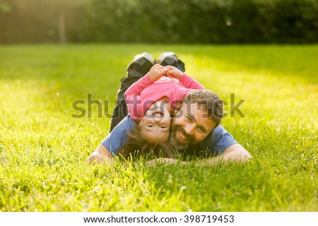 Devoted father and daughter lying on grass, enjoying eachothers company, bonding, playing, having fun in nature on a bright, sunny day. Parenthood, lifestyle, childhood and family life concept.