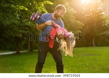Devoted father spinning his daughter in circles, bonding, playing, having fun in nature on a bright, sunny day. Parenthood, lifestyle, parenting, childhood and family life concept.