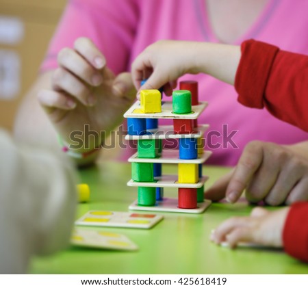 Children playing with homemade, do-it-yourself educational toys, stacking and arranging colorful pieces. Learning through experience concept, gross and fine motor skills, back to school concept.