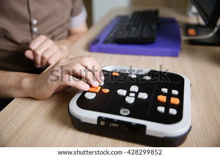 Blind person using audio book player for visually impaired, listening to audio book on his computer. Blindness aid, visual impairment, independent life concept.
