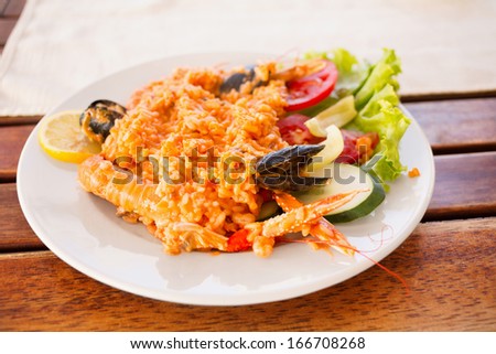 Serving plate with rice, shrimps and salad/Colorful dishware with seafood and vegetables. Delicious seafood serving on picnic table.
