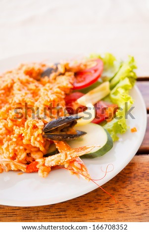 Serving plate with rice, shrimps and salad/Colorful dishware with seafood and vegetables. Delicious seafood serving on picnic table.