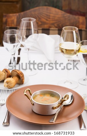 Mushroom soup/A bowl of creamy mushroom soup. Serving plate with mushrooms and glasses of white wine.