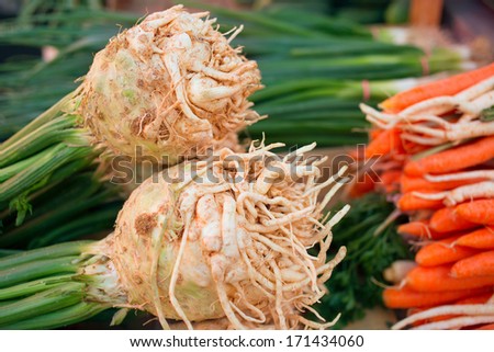 Celery and carrots on market place/Root vegetable arranged for selling on stand. Fresh raw carrots and onion ready to buy.