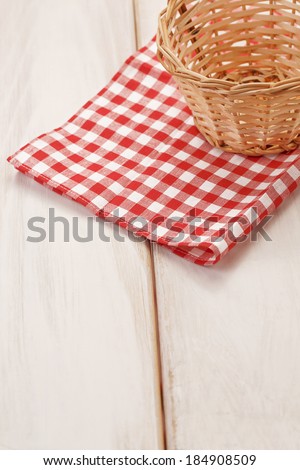 Basket on picnic table/Close up of basket on wooden table. Red plaid cloth
