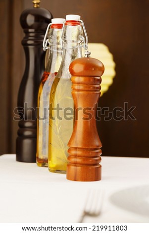Bottles of olive, vinegar and spice arranged in restaurant. Shallow depth of field for soft background/Pepper and salt. Olive oil with spice.