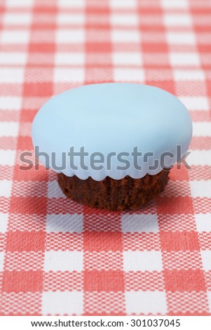 Chocolate cupcake covered with blue fondant. Cupcake on picnic table./Chocolate blue cupcake
