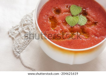 Cold tomato soup gazpacho in cup closeup on lacy napkin