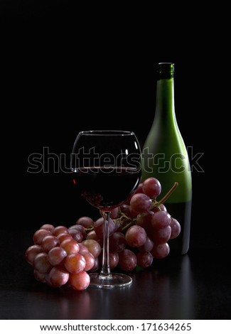Still life in the Italian style of wine, glass and grapes on a black background