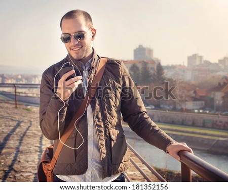 Young man using a smart phone outdoors / white balance correction in photo shop, focal point is on the young man\'s face.