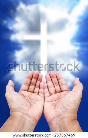 Prayer raised hands on cloudy cross background.