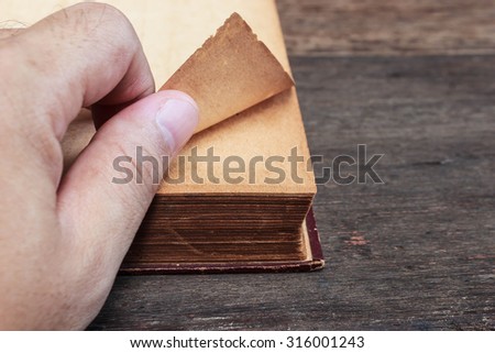 Fingers holding corner of vintage book.