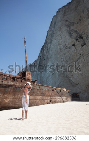 Woman in skirt and a hat on background a ship wreck