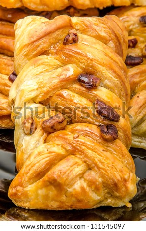 Some pastries filled by honey syrup and sprinkled by pecan nuts on black plate
