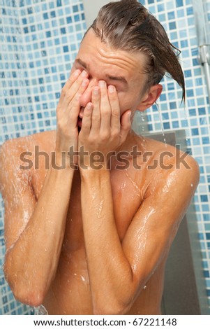 Half body portrait of young man washing face and body in shower