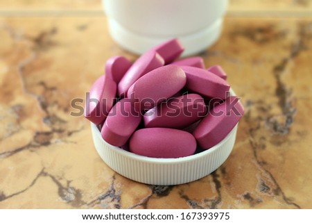 Tablets. Vitamins. Dietary supplement. Pink tablets, vitamins, dietary supplement in the lid from a bottle