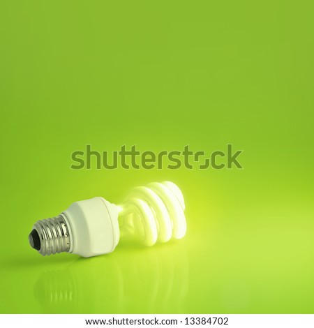 A vibrant presentation of a modern energy-saving lightbulb lit on a lush green background.  Plenty of copyspace, ideal for ecology, energy concepts or imagination and marketing pitches