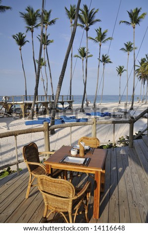 Table at a restaurant in the caribbeans, overlooking the ocean and palm trees on a white sand beach
